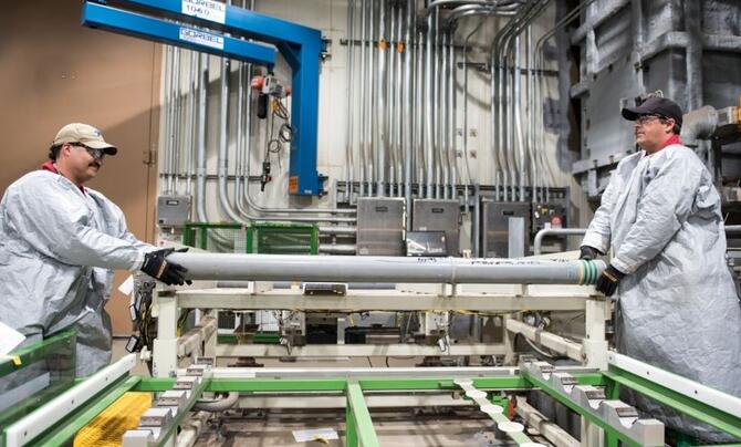 Two workers load the last remaining U.S. chemical munition into a demilitarization system