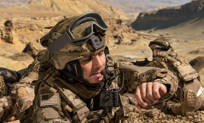 Soldier crouching and looking at his watch