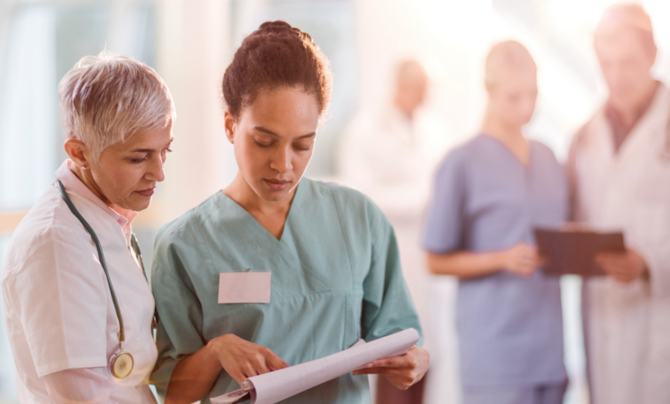 A doctor and a nurse talking and looking at a piece of paper