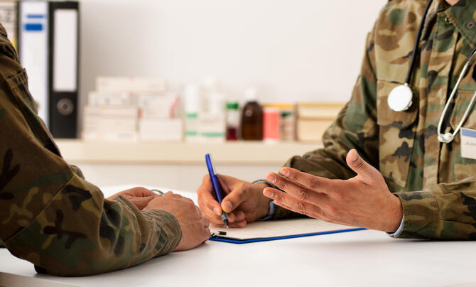Two military officers chatting and filling out a form