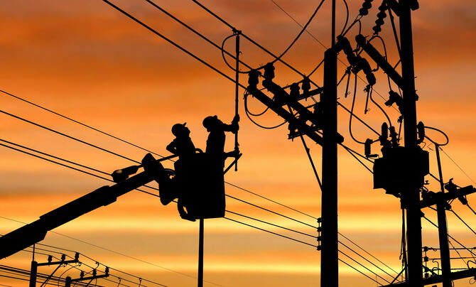 Line workers in silhouette 