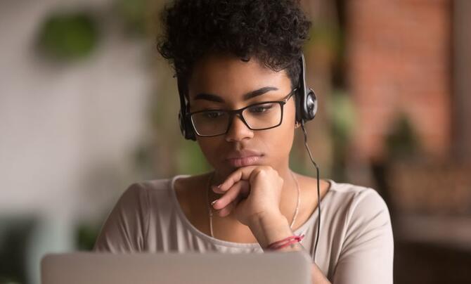A teenager wearing headphones while taking an online course