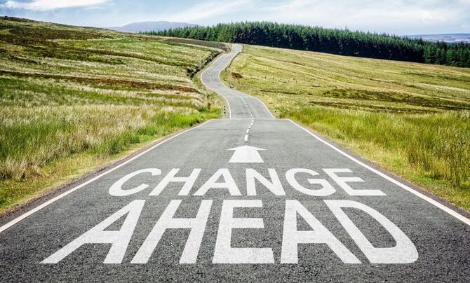 A rural highway with the words "Change Ahead" painted on the road