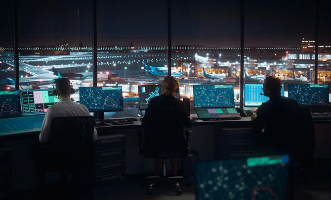 view from behind 3 employees working in a airport tower