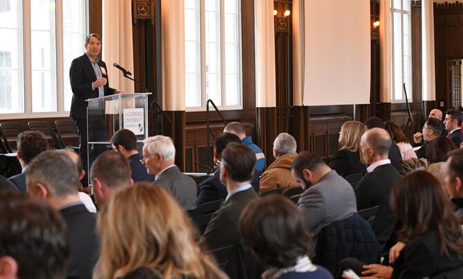 man at podium speaking to crowd in a building
