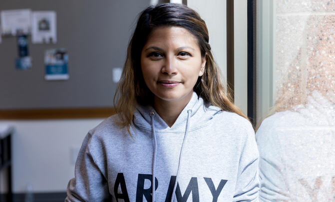 woman standing by window in army hoodie