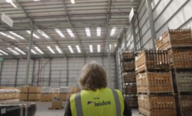 woman in vest standing in warehouse of boxes