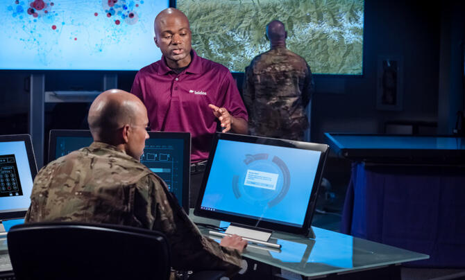 Leidos employee assists military personnel with technology.