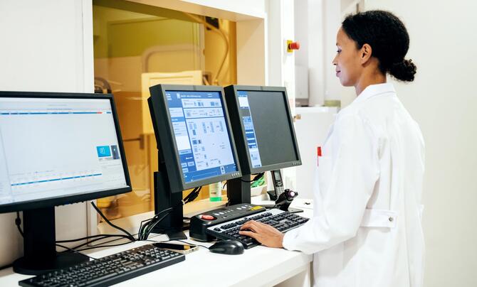 A doctor standing while using a computer in the radiology department at hospital.