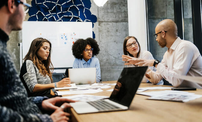 group of 5 people sitting at table collaborating