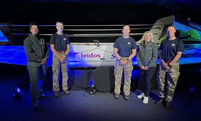 five people stand in front of a boat