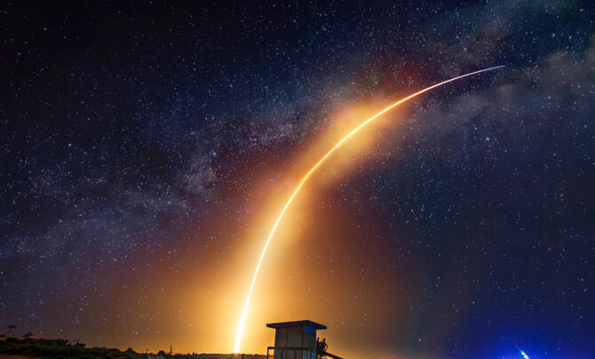 A missile shoots across the sky, leaving a bright tail behind.