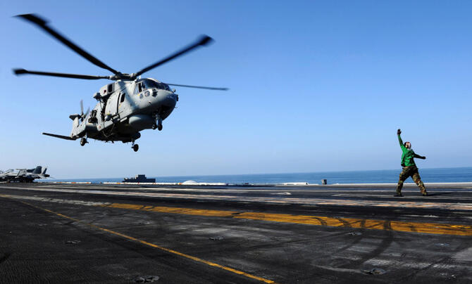 helicopter being guided to landing next to ocean