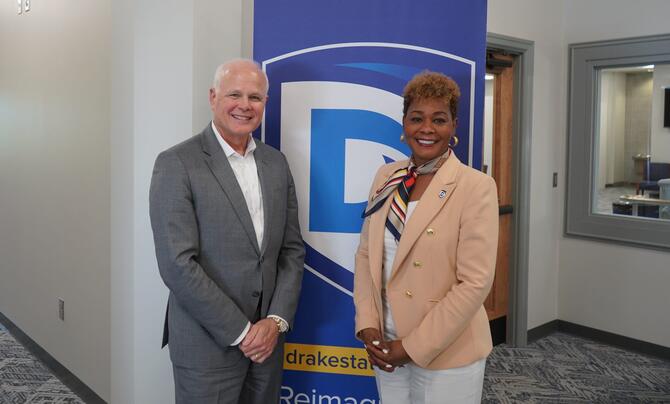Leidos CEO Tom Bell and Drake State President Dr. Patricia Sims pose in front of a Drake State banner.