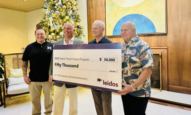 Four men holding an oversized check for $50,000. 
