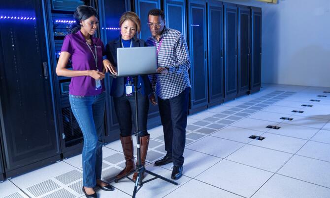 three employees in front of network racks