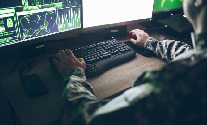 A person in military uniform works on a computer.
