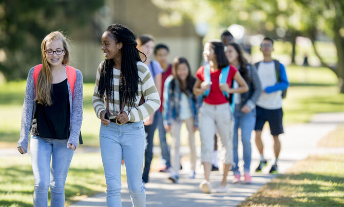 A multi-ethnic group of high school age students are walking to class together before school.