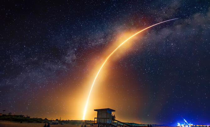 A rocket leaves a fiery trail in the sky.