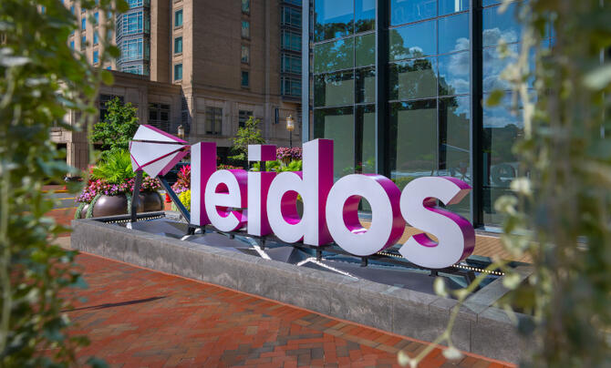 The Leidos sign is viewed in between spring flowers.