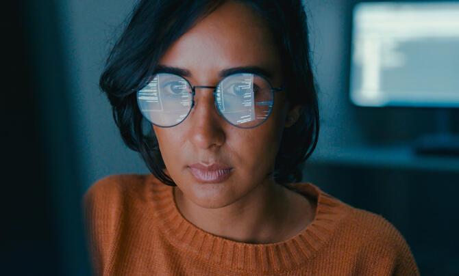 Female computer programmer works on complex software development tasks at her home office late into the night