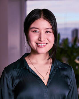 A woman in a green shirt smiles at the camera