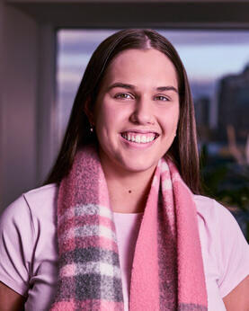 A woman with a pink scarf smiling at the camera
