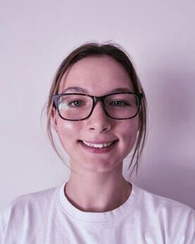 A woman in a white tshirt and glasses smiling at the camera