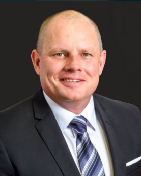 A man in a suit smiles at the camera