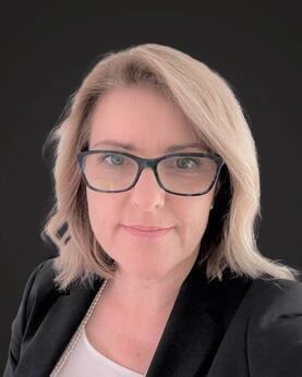 A blonde woman wearing glasses looking at camera