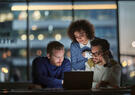 Three technology professionals collaborating around a laptop.