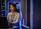 Woman in data center working on a laptop.