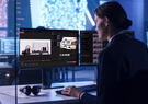 A security analyst reviews vehicle scan images and data on multiple monitors in a high-tech screening and inspection environment.
