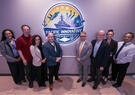 A group of professionals stands together beneath the Pacific Innovative Cooperative logo during a partnership or organizational event.