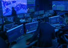 A cybersecurity operations center with analysts monitoring real-time dashboards and global network activity across multiple screens to detect and respond to cyber threats.