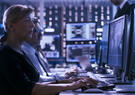 Cybersecurity analysts monitor network activity from a security operations center, using multiple screens displaying maps, dashboards, and threat data to detect and respond to potential cyber threats.