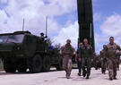 U.S. military personnel and officials walk past a Dark Eagle long-range hypersonic weapon launcher during the Valiant Shield exercise, with the mobile launcher and support vehicle positioned beside the roadway.