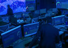 Cyber operations center with analysts monitoring multiple dashboards and global network activity across large display walls, supporting real-time cybersecurity monitoring and threat detection.