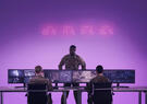 Military personnel monitor geospatial imagery and data across multiple screens in an operations center, illustrating the use of AI-enabled analysis for situational awareness.