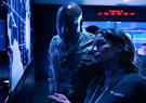 U.S. Air Force service member and Leidos employee analyze data on large digital displays in a military cyber operations center.