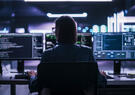 Woman sitting at a computer desk in front of three monitors