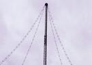 The top part of a thin lattice-type metal tower with four wire lines leading to the very top - this is ALPS (Army Long-Range Persistent Surveillance) system is a passive, long-range aerial surveillance sensor developed by Leidos