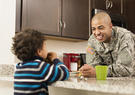 Military man in uniform in kitchen with kid