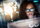 woman looking at screen with reflection of screen on her glasses