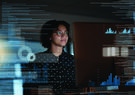 Woman with holographic information in front of computer screen