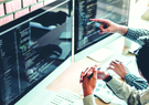 two people discussing code shown on computer screens