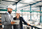 Two people in an industrial environment looking at a tablet