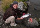 Adak tribe member holding salmon and smiling at camera