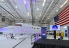 The Artemis II aircraft in a hanger with an American flag draped in the background