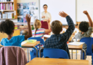 Children in a classroom raising their hands